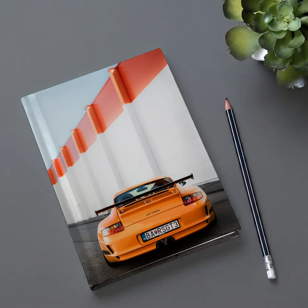 Porsche GT3 RS Orange Against Industrial Wall – Notebooks