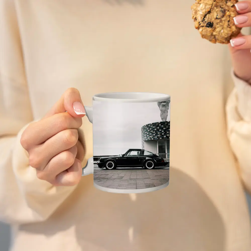 Black Porsche 911 Parked by Coastal Building – Mugs