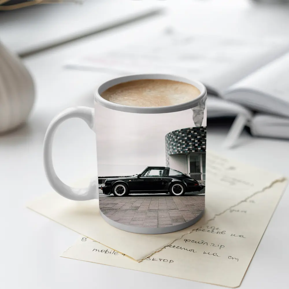 Black Porsche 911 Parked by Coastal Building – Mugs