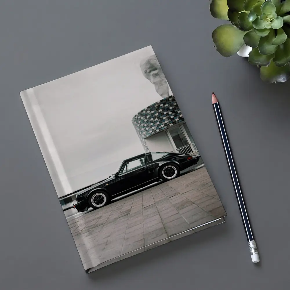 Black Porsche 911 Parked by Coastal Building – Notebooks