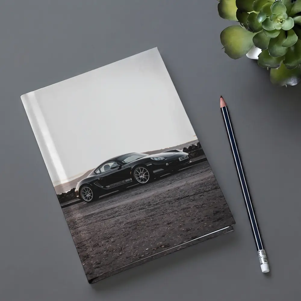 Black Porsche Cayman Parked on Rugged Terrain – Notebooks