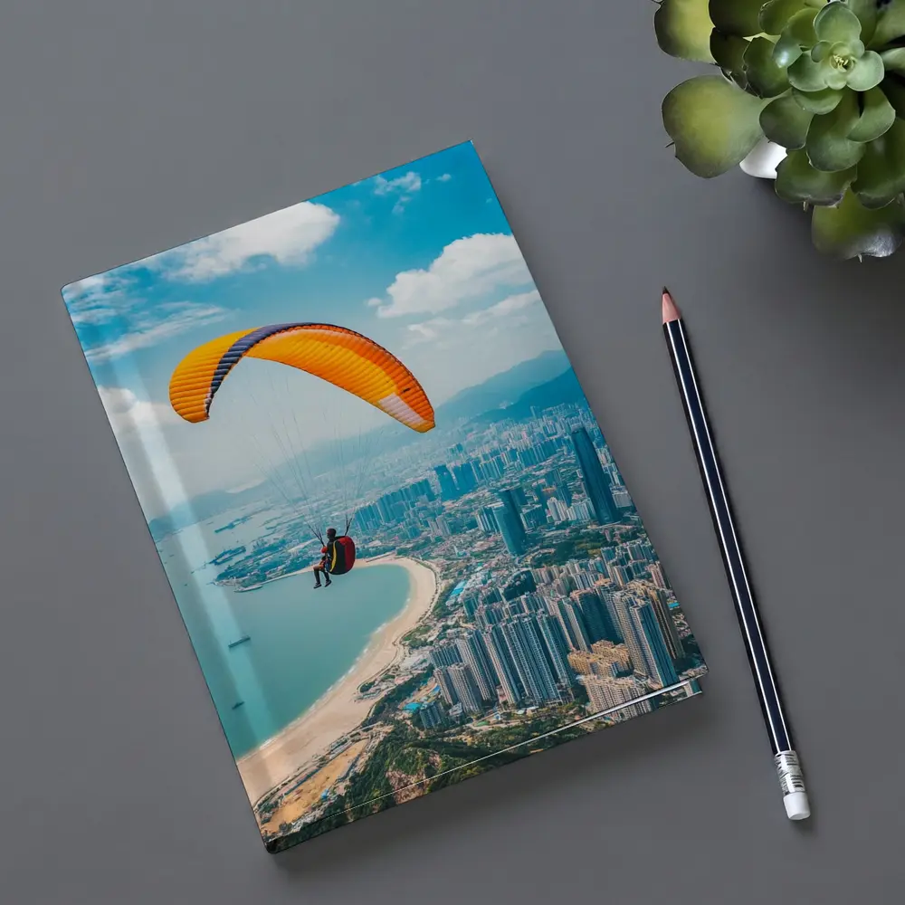 Paraglider Soaring Over Coastal City Skyline – Notebooks