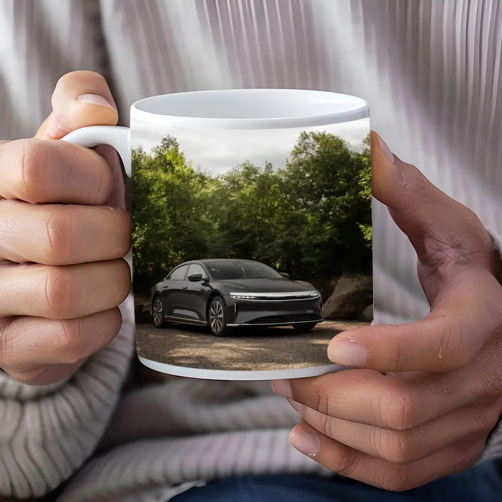 Lucid Air Dark Sedan Parked Among Trees – Mugs