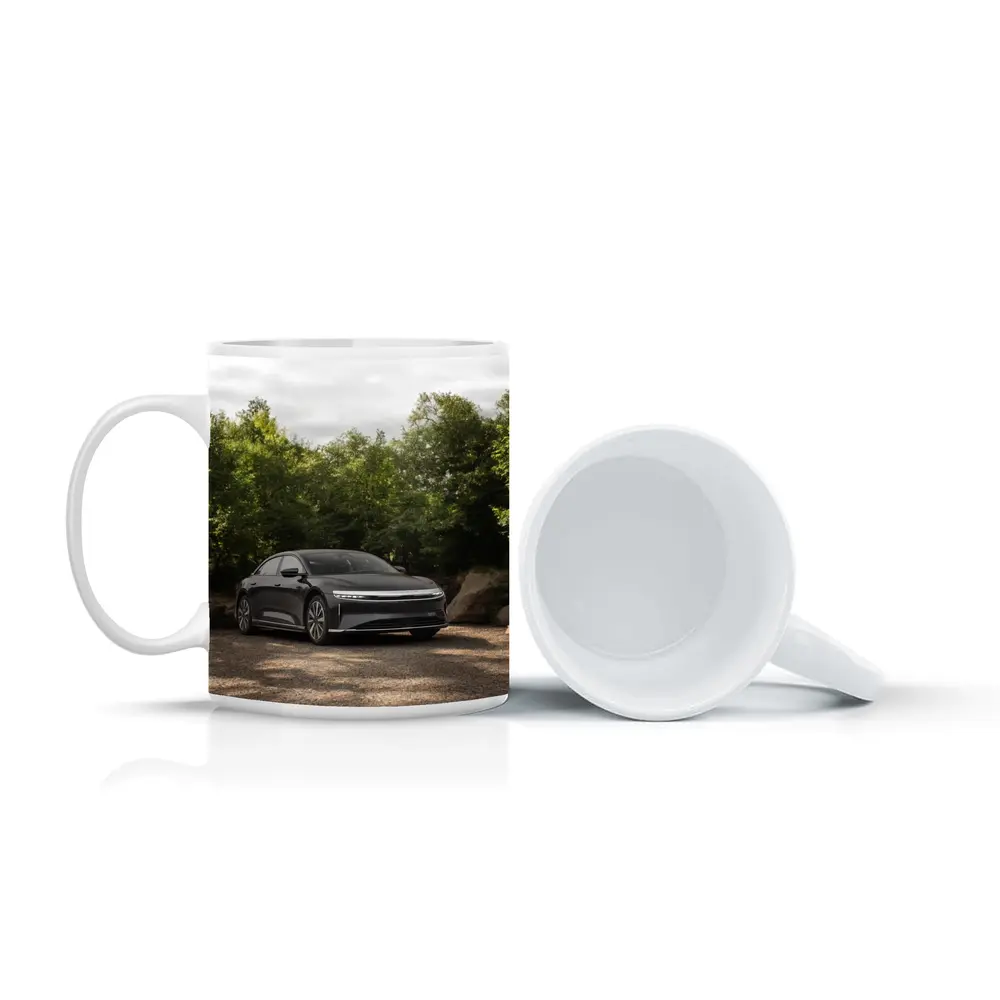Lucid Air Dark Sedan Parked Among Trees – Mugs