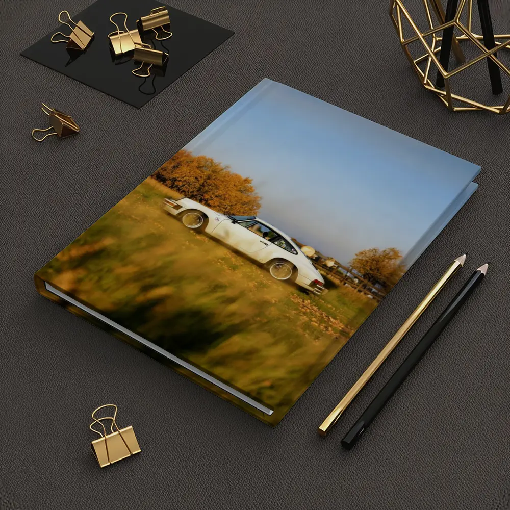 White Porsche 911 Parked in Autumn Field – Notebooks