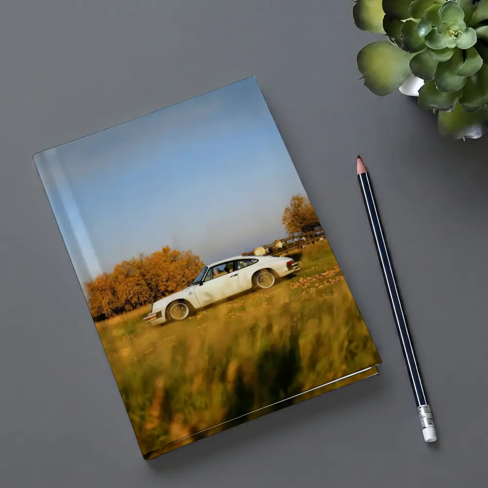 White Porsche 911 Parked in Autumn Field – Notebooks