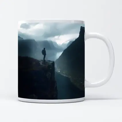 Hiker Standing On Cliff Above Misty Fjord