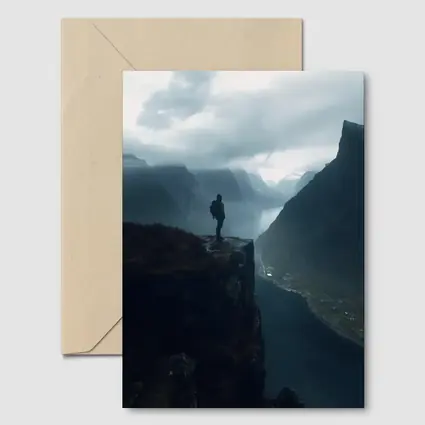 Hiker Standing On Cliff Above Misty Fjord