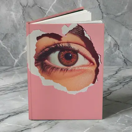 Brown Eye Peering Through Torn Pink Paper